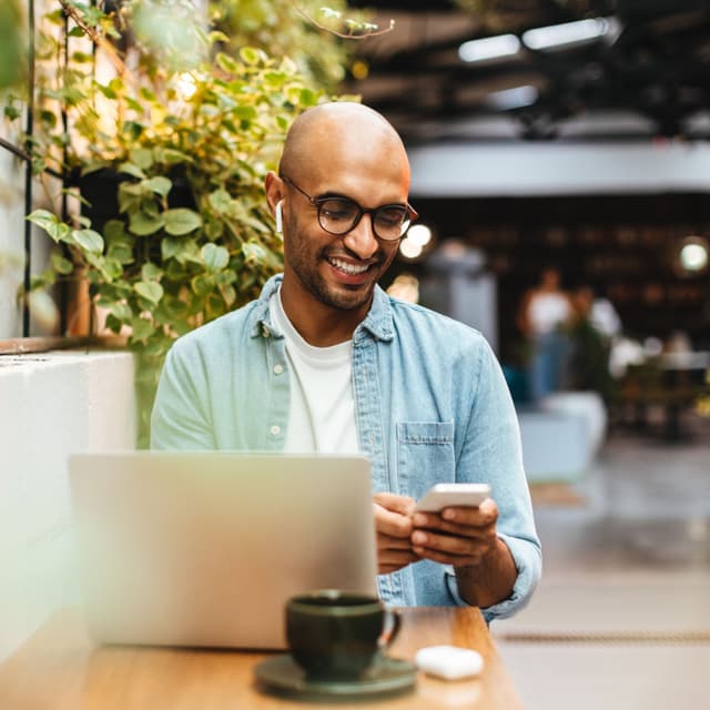 Young professional using a laptop at a café, researching cover letter tips on how to write a cover letter for job applications.