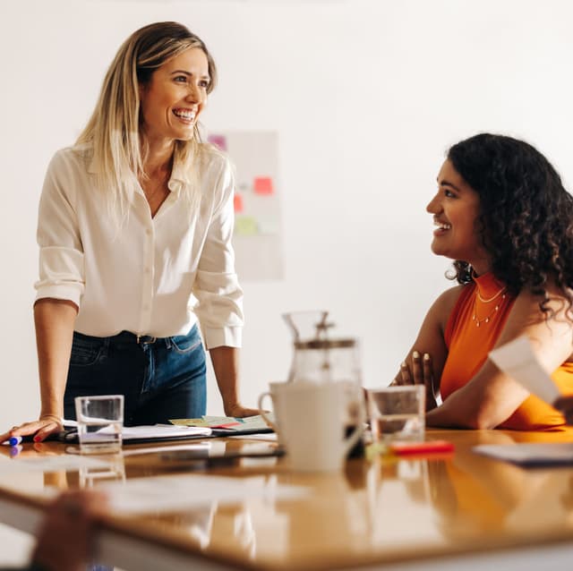 Female leader confidently engaging with a colleague in a team meeting, demonstrating effective leadership skills.